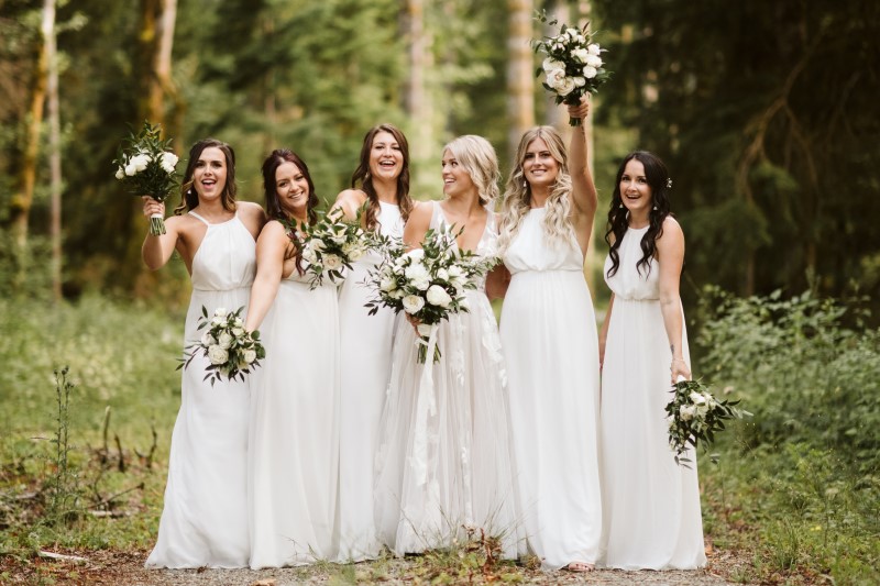 Bride and Bridesmaids in white dresses carrying bouquets of white roses and italian ruscus on Vancouver Island