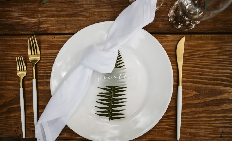 White reception plate on wood table with green fern leaf by Party Mood Vancouver Island