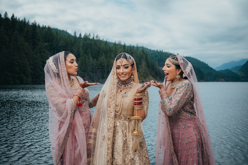 Indian Bride and Bridesmaids playfully pose in front of Rocky Mountain Lake by Dreamfinity Studios