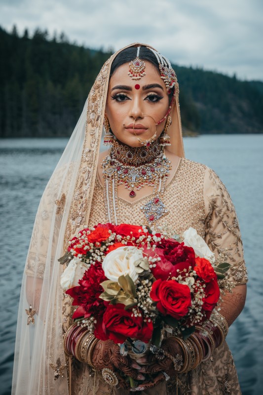 Bride in traditional Indian Saree holding bouquet of red roses 