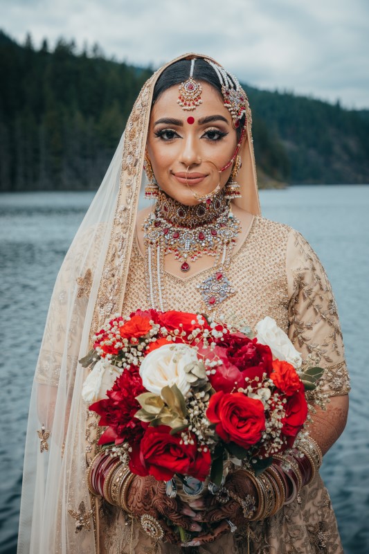 Coastal Luxury Indian Bride smiles while holding bouquet of red roses