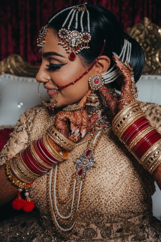 Indian Bride covered in jewelery and wearing blush saree by Dreamfinity Studios