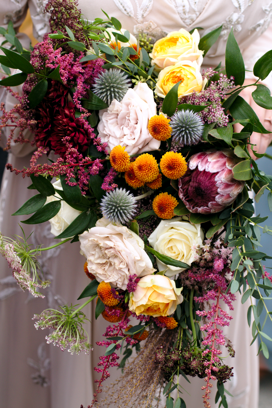 Pink Protea, blue thistle, white roses bridal bouquet by Bespoke Blossoms