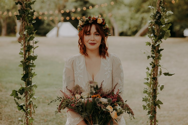 Charming Farm Wedding bride sitting on ivy swing with bouquet by LumiPhoto