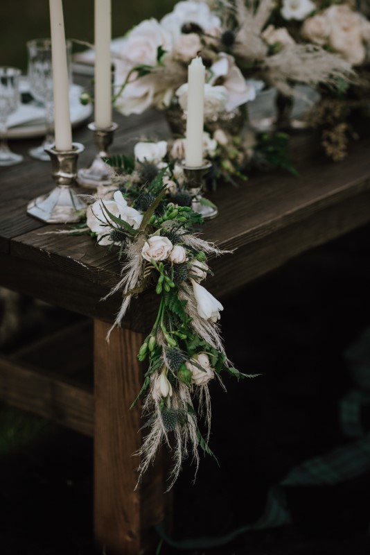 White rose garland on brown wood table by bespoke blossoms