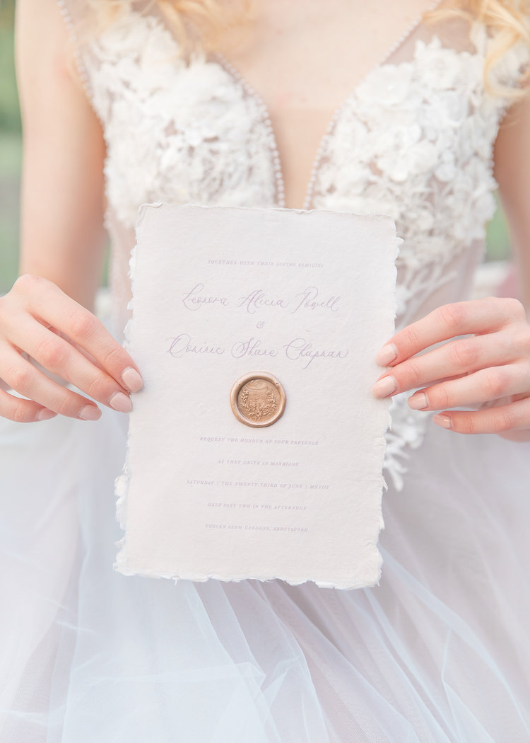 Bride holds embossed wedding paper suite by The Ayla View