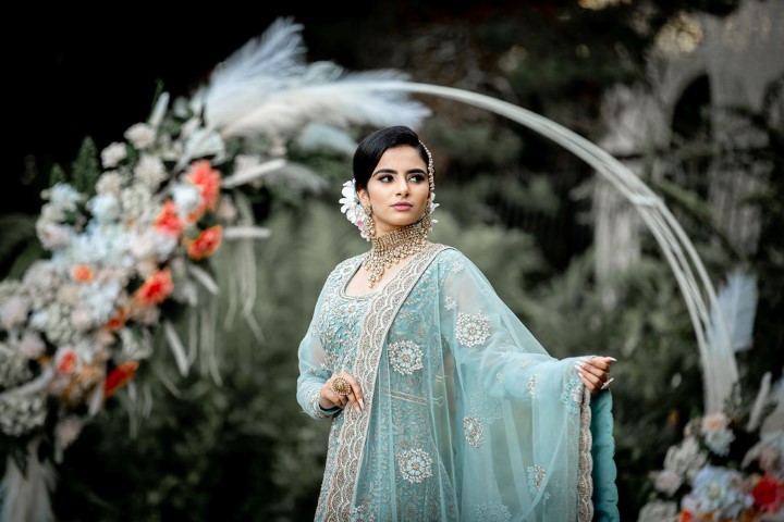 Indian Bride holds out her ice blue and white lace sari in front of wedding hoop