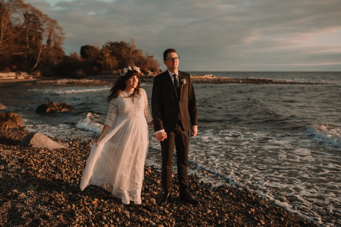 Newlyweds brace against the wind on the Sunshine Coast beach near Vancouver