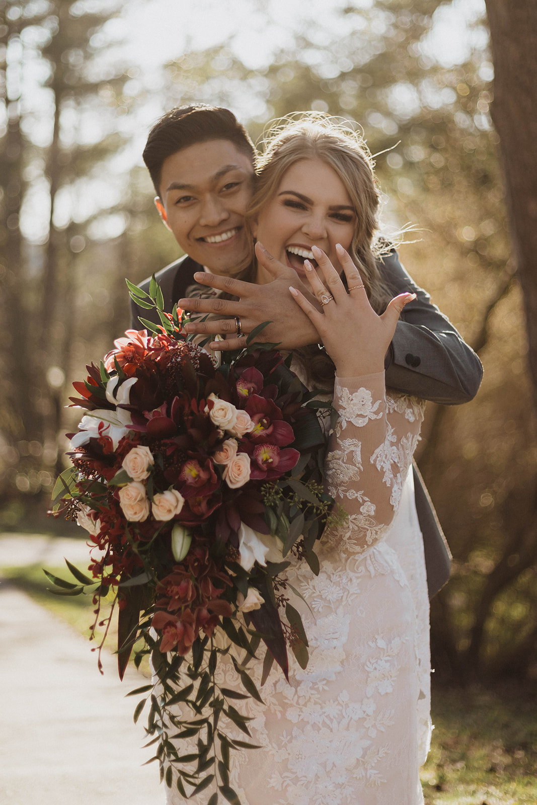 Bride shows off wedding ring wearing lace form fitting gown with veil