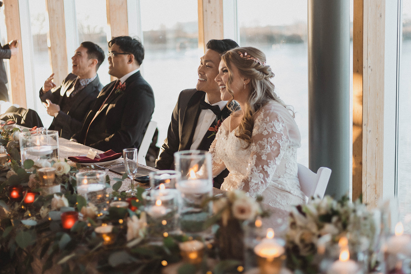 UBC Boathouse Couple sit at head table with Vancouver waterfront behind them by Kacie McColm 