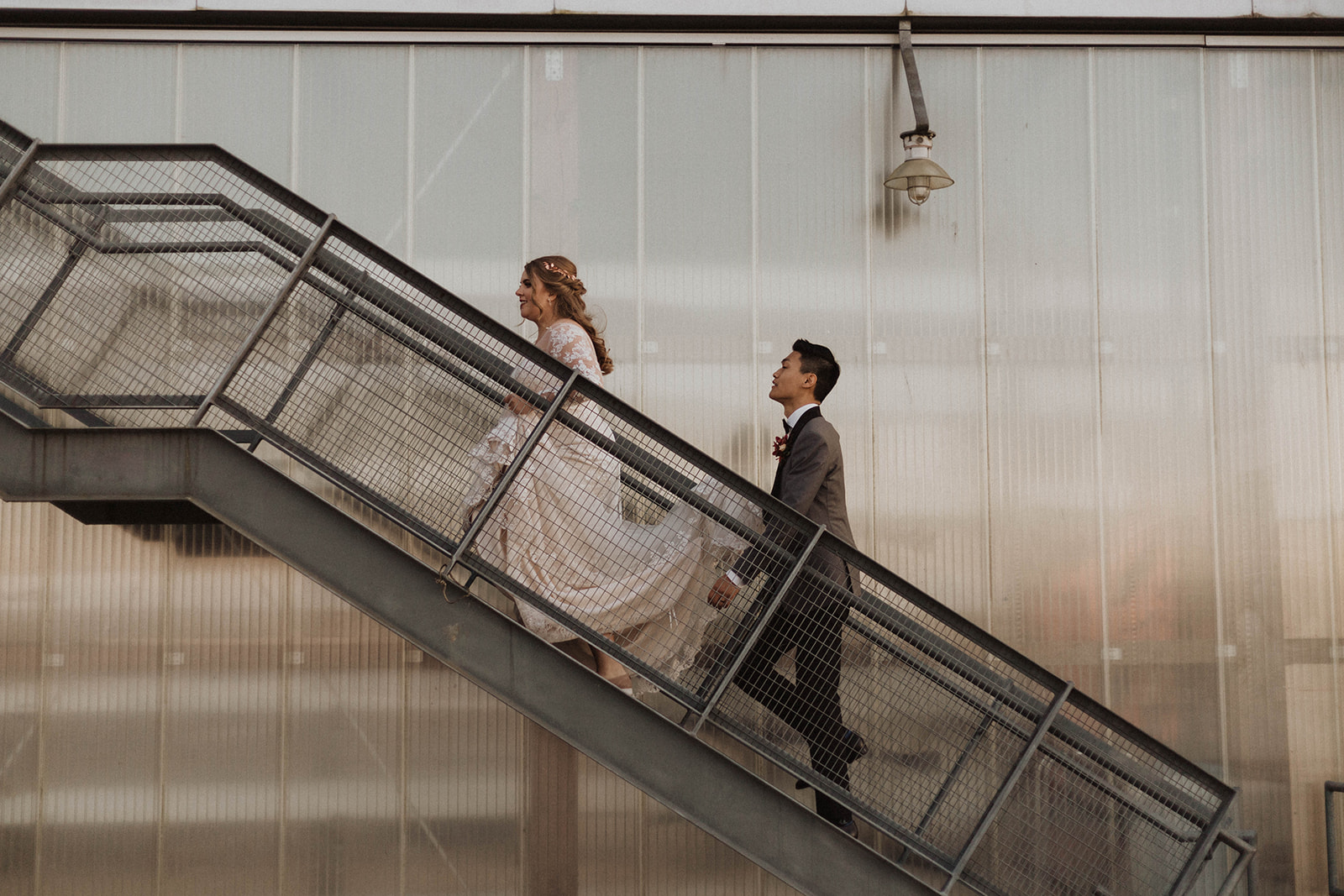 UBC Boathouse wedding couple walk up the metal staircase to reception in Vancouver