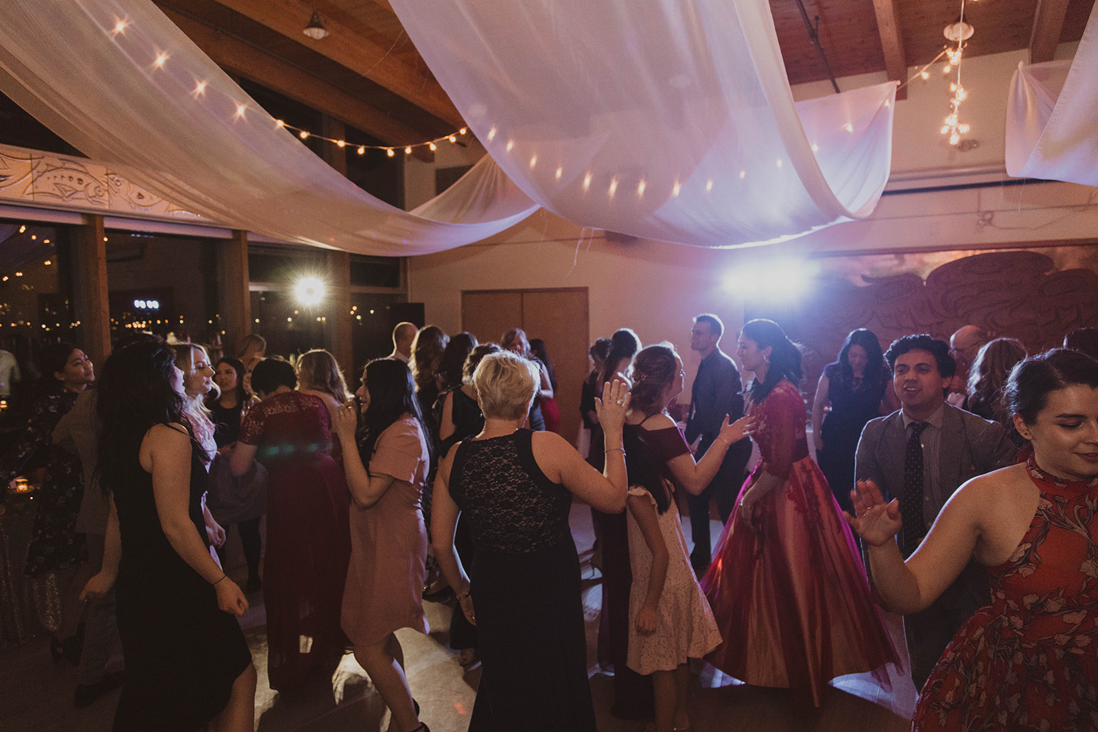 UBC Boathouse Wedding guests dance under white fabric ceiling treatment and industrial lights by Proline International Trading Vancouver