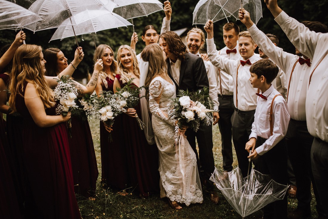 A Farm Table Wedding party laughs under umbrellas by Wild Oak Collective