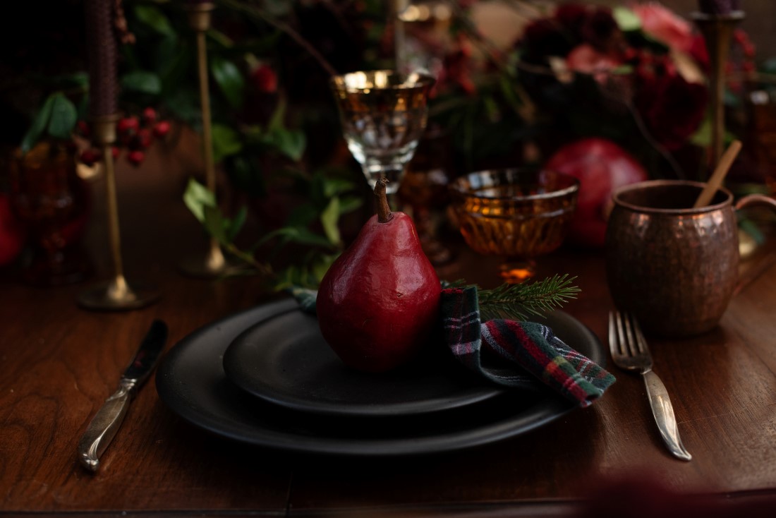 Burgundy Pear atop black plates on wood wedding reception table by Urban Fig PHotography