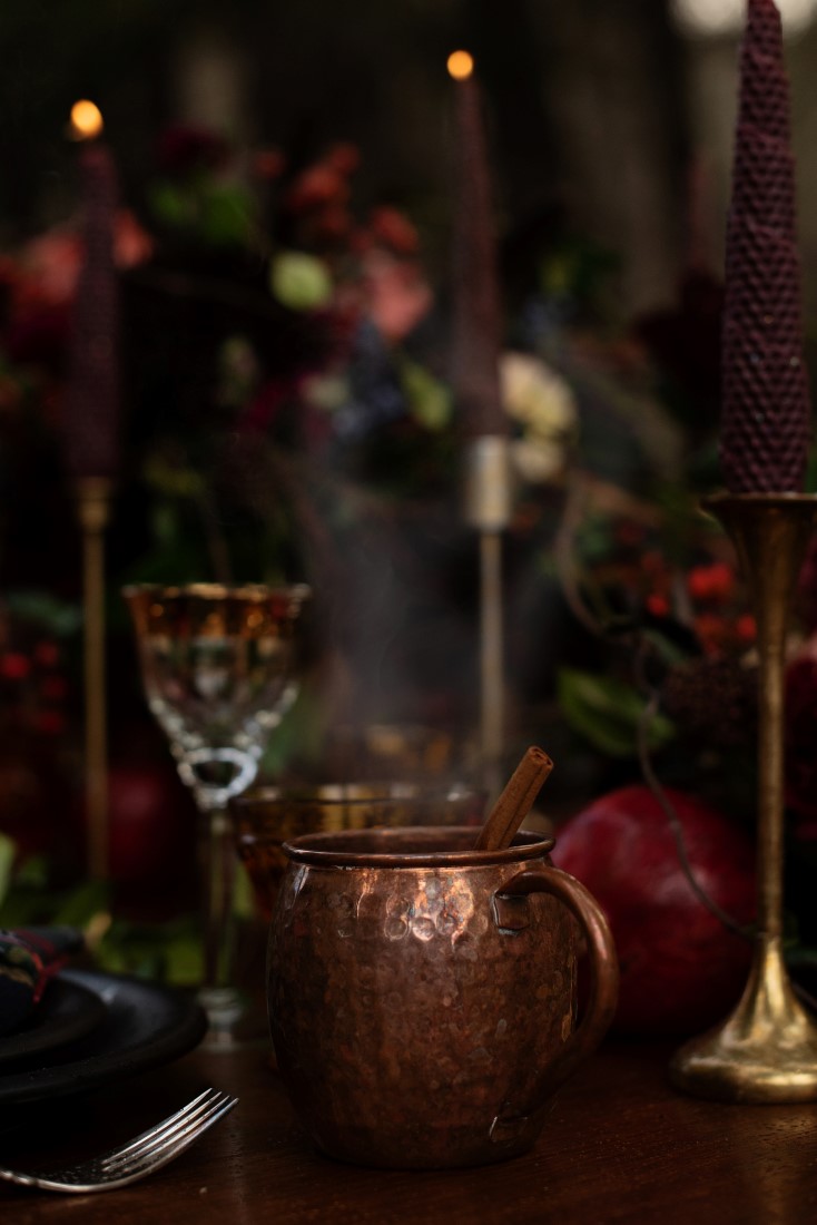 Deep Gold Jar and pomegranate sit on wood table with burgundy taper candles and gold candlesticks