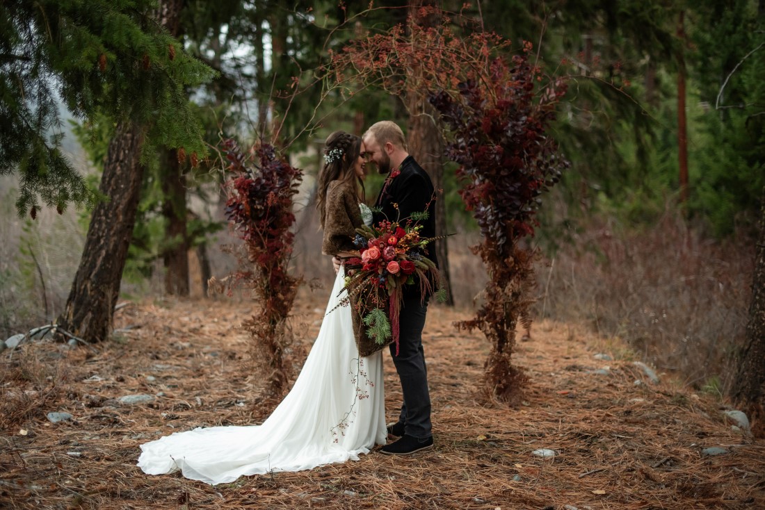 Magical Woodsy Wedding Inspiration couple in front of arch of orange berries by Thistle and Thorne Weddings Vancouver