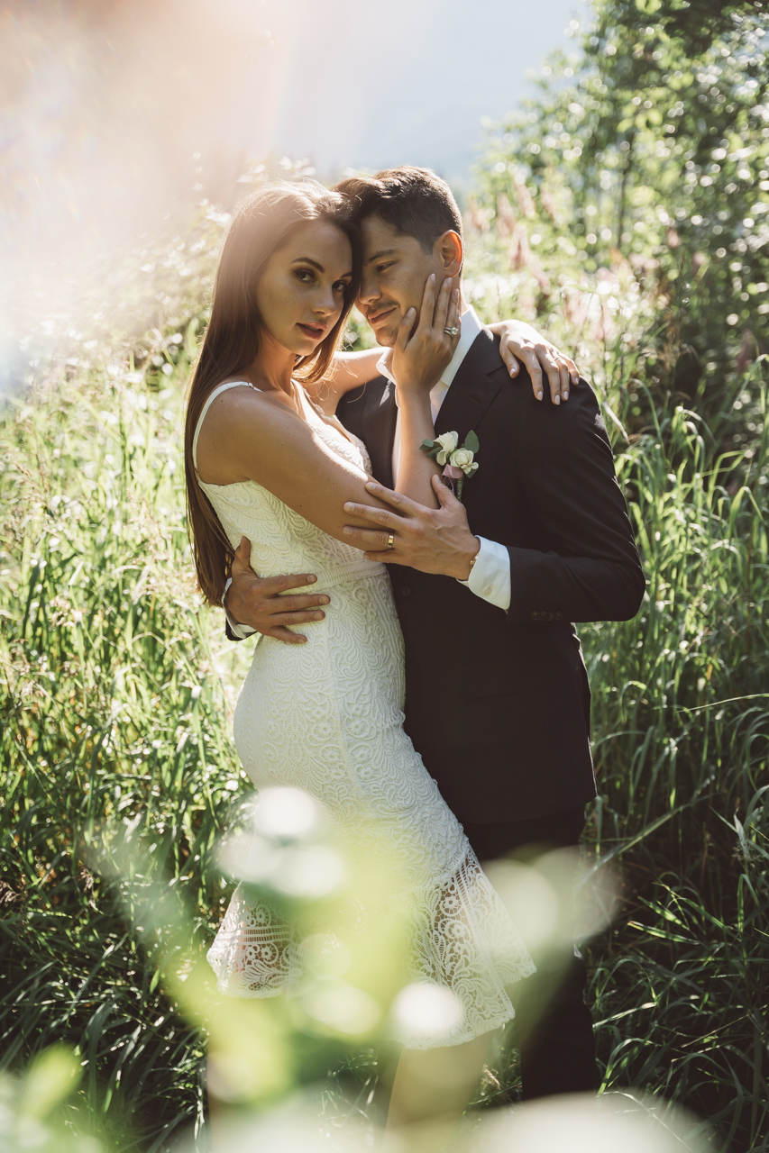 Newlyweds hold each other in long green grass at Whistler