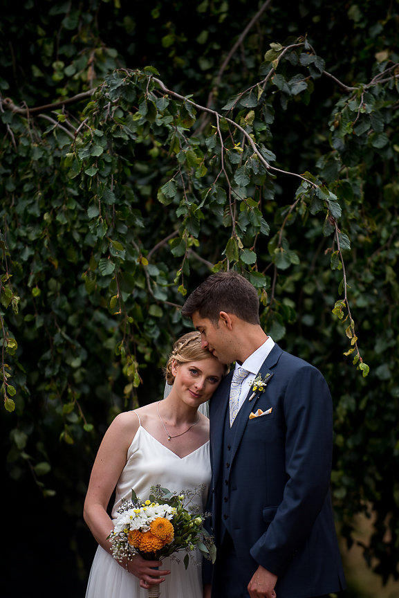 Newlyweds stand in front of trees and smile by Meghan Andrews PHotography