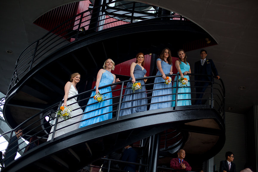 Bridesmaids in blue gowns line an infinity staircase at False Creek Yacht Club Vancouver