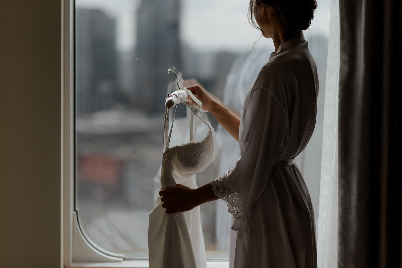 Bride holds her wedding gown in front of Vancouver cityscape