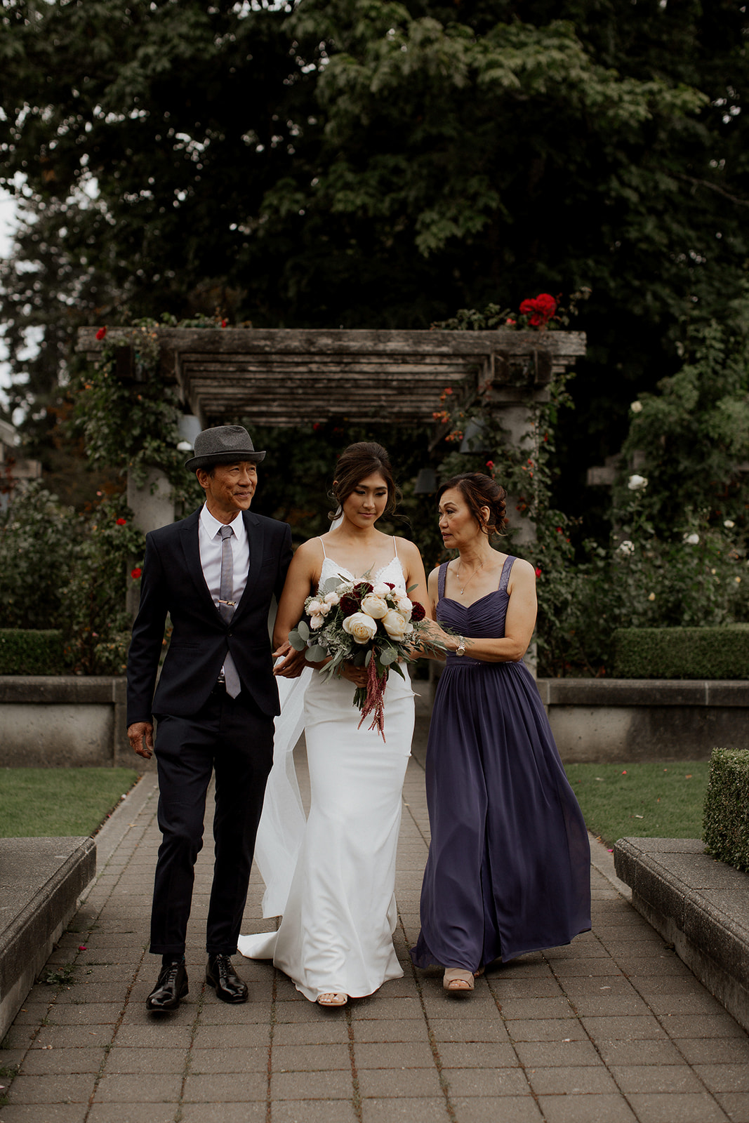 Bride is walked down the aisle by both parents at UBC Rose Garden Ceremony