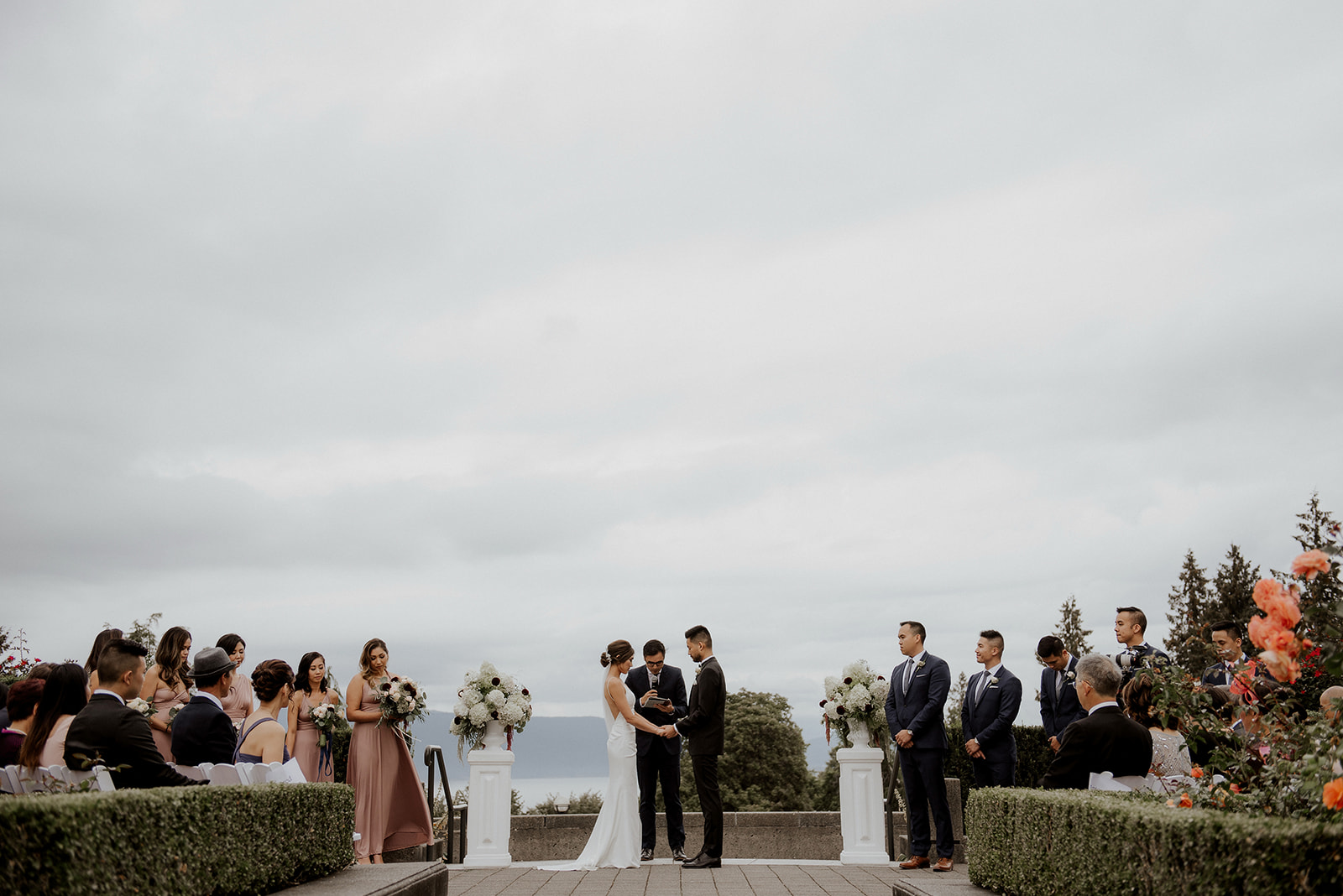 Newlyweds stand in front of guests at UBC Rose Garden by Kaoverii Silva Photography 