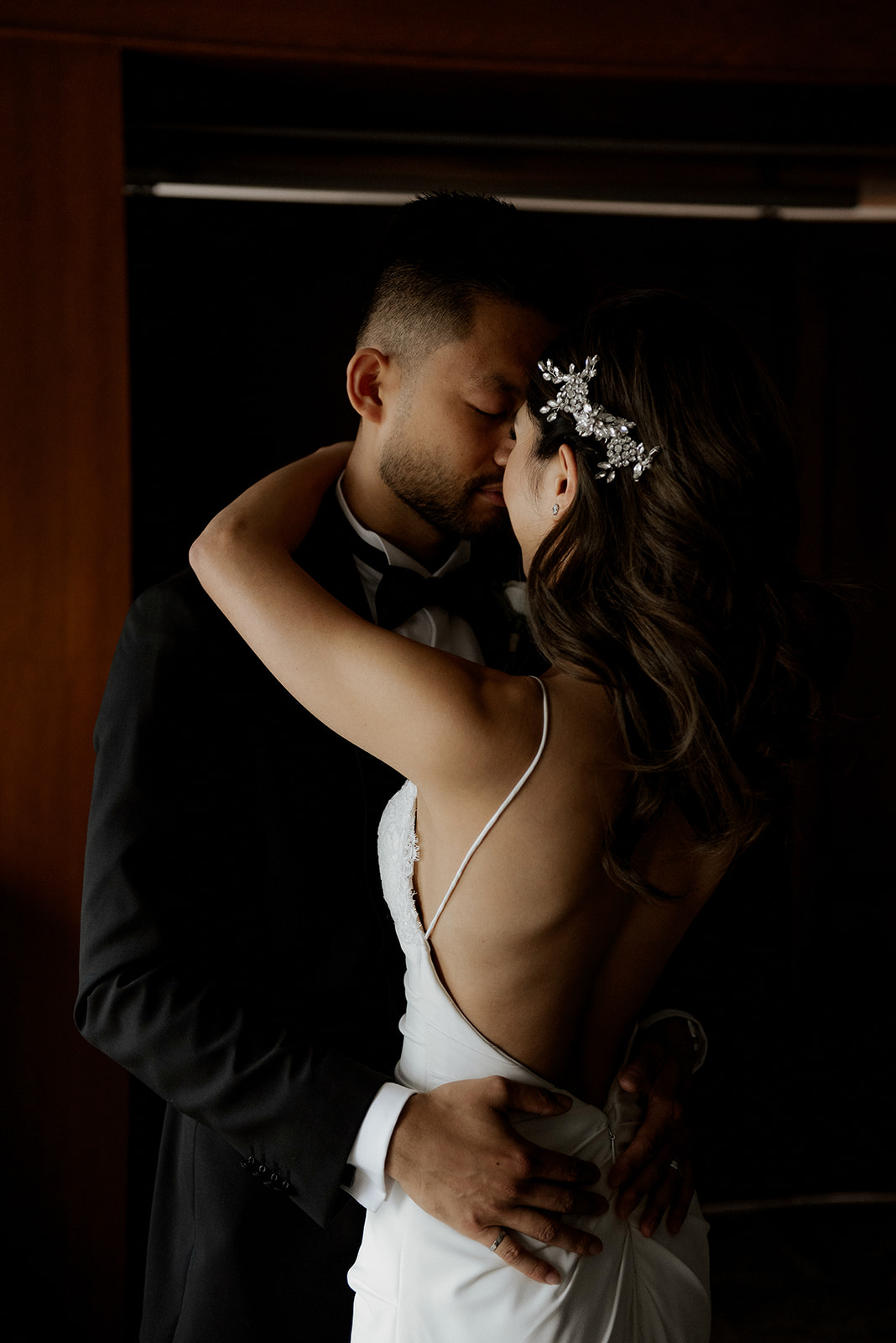 Newlyweds embrace and kiss in the shadows by Kaoverii Silva Photography