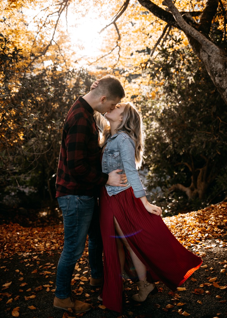 Bride to be in jean jacket and burgundy dress kissed by husband to be Evergrey Photography