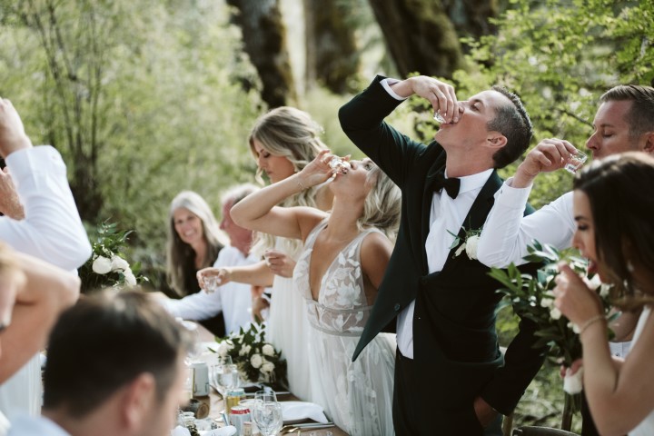 Bride and groom drink a toast at forest wedding reception by Truffles Catering Vancouver Island