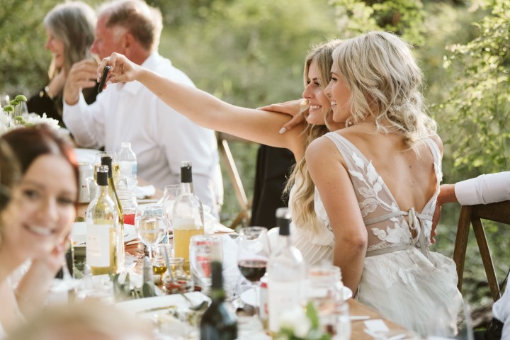 Bride and friend taking a selfie at forest wedding reception