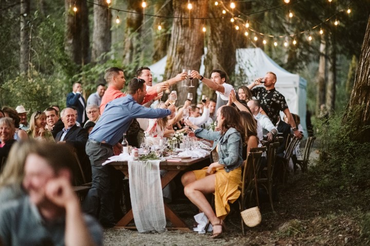 Guests toast the bride and groom at forest reception on Vancouver Island