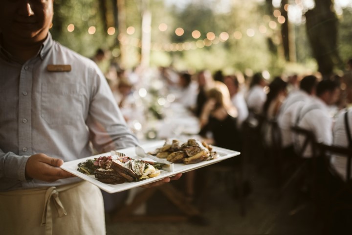 Waiter serves wedding main course to forest reception long table Truffles Catering Vancouver Island