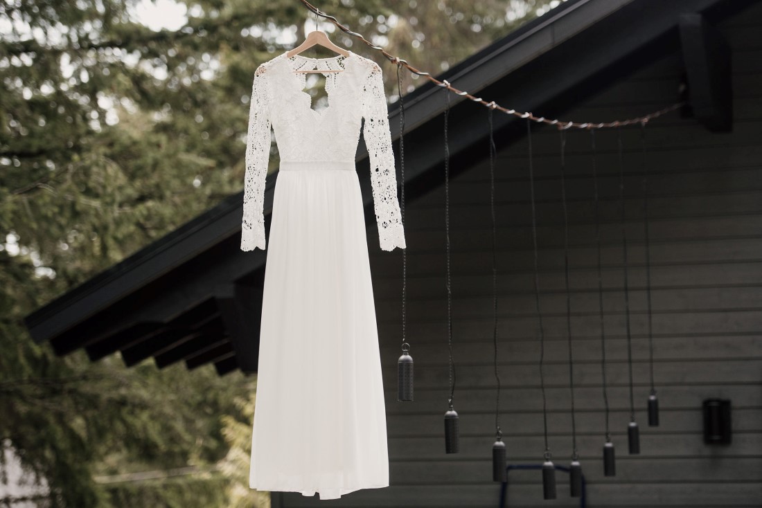 Bridal gown hangs from a tree by West Coast Weddings Magazine