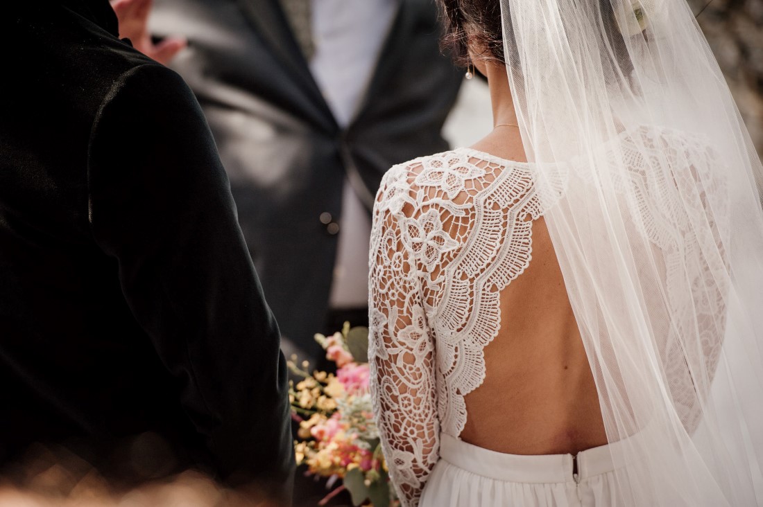 Bride wears lace bodice with back cut out and long veil by Emily Serrell