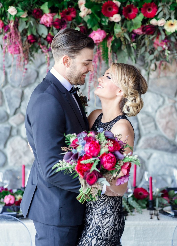 Floral backdrop behind wedding couple by Joanna Moss Photography