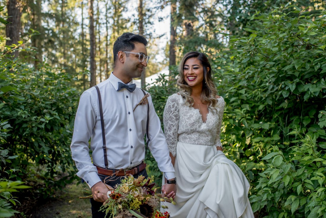 Bride and Groom walk through the woods hand in hand