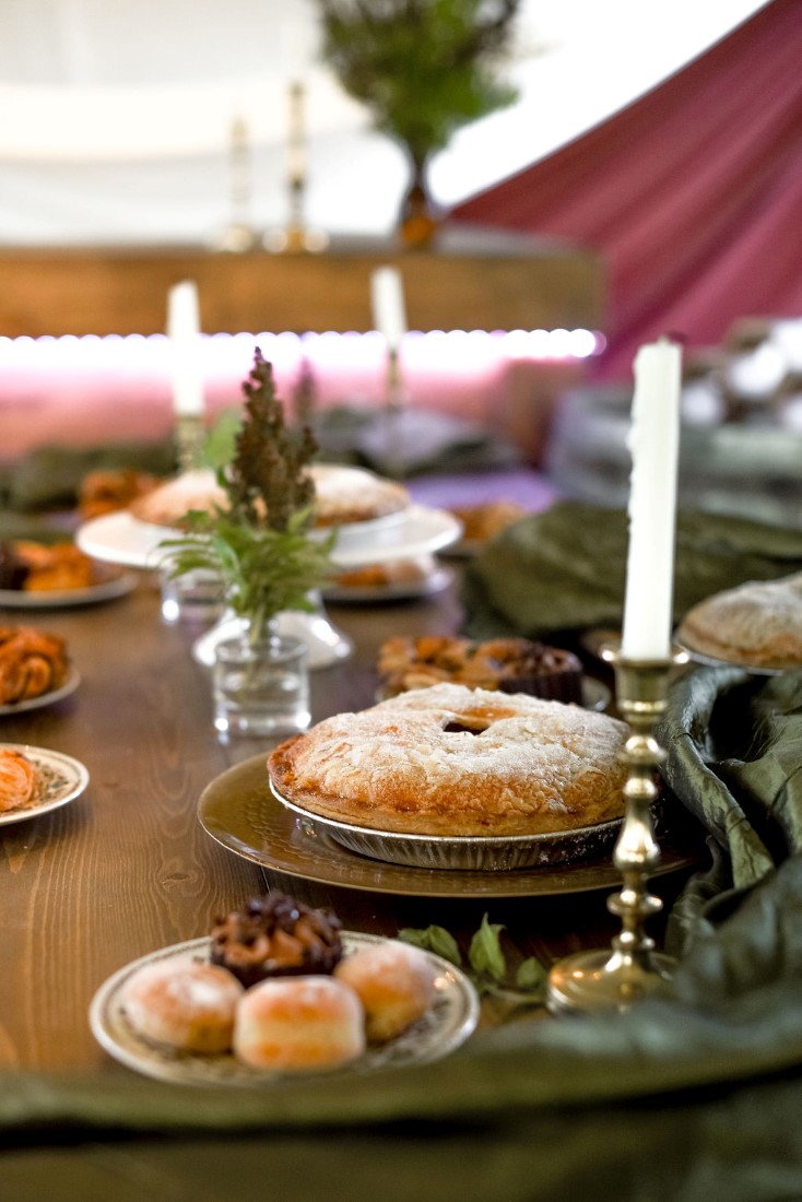 Pie sits on trestle wedding reception table with candles and greenery