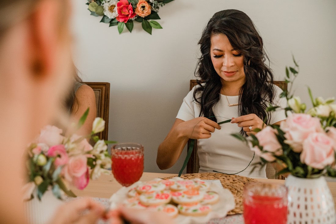 Bride threads flowers on to floral crown at her bridal shower