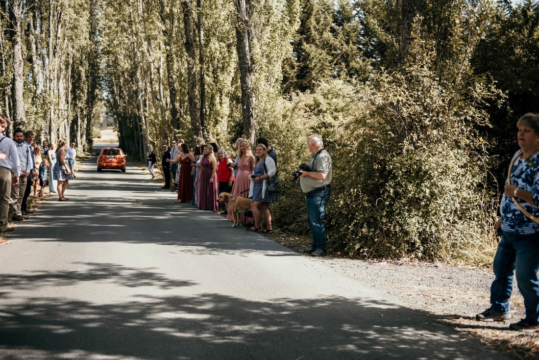 Guests line the road to wave at bride and groom at Covid-19 wedding