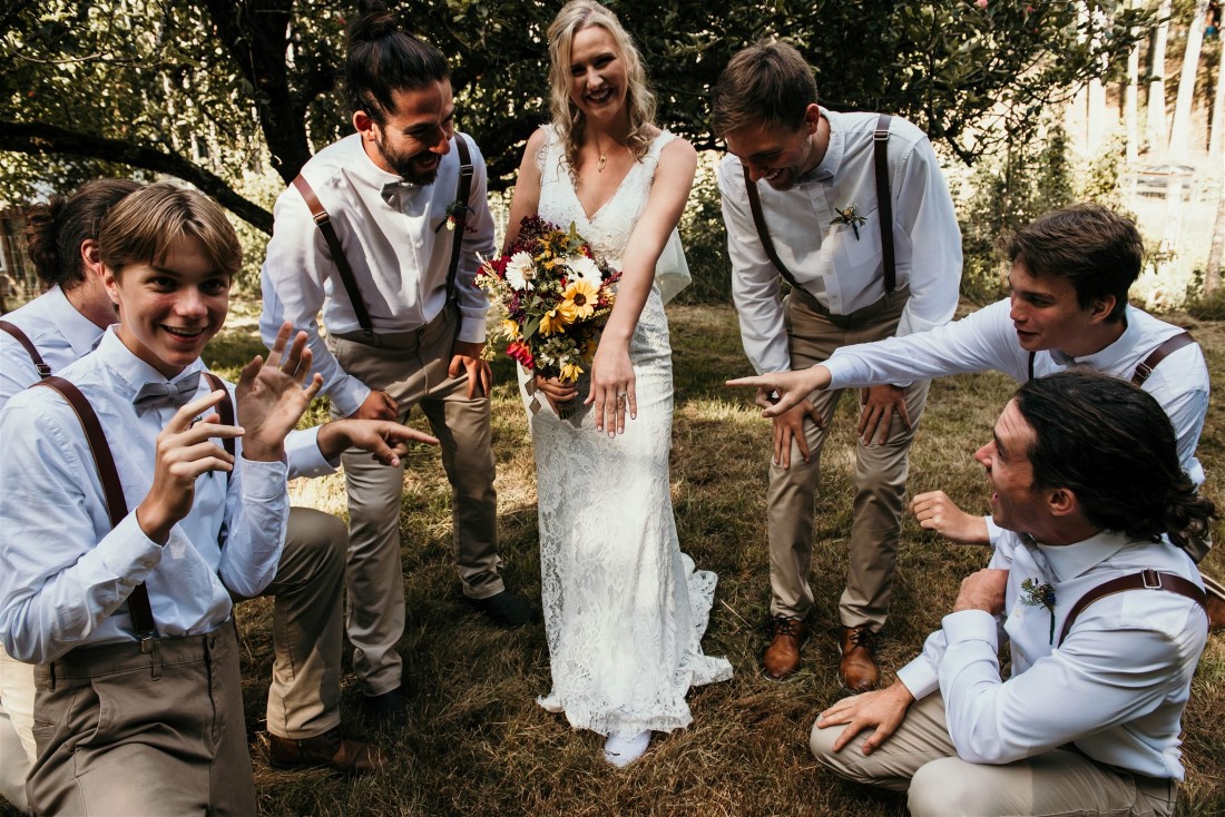 Bride surrounded by groomsman wearing brown tweed vests