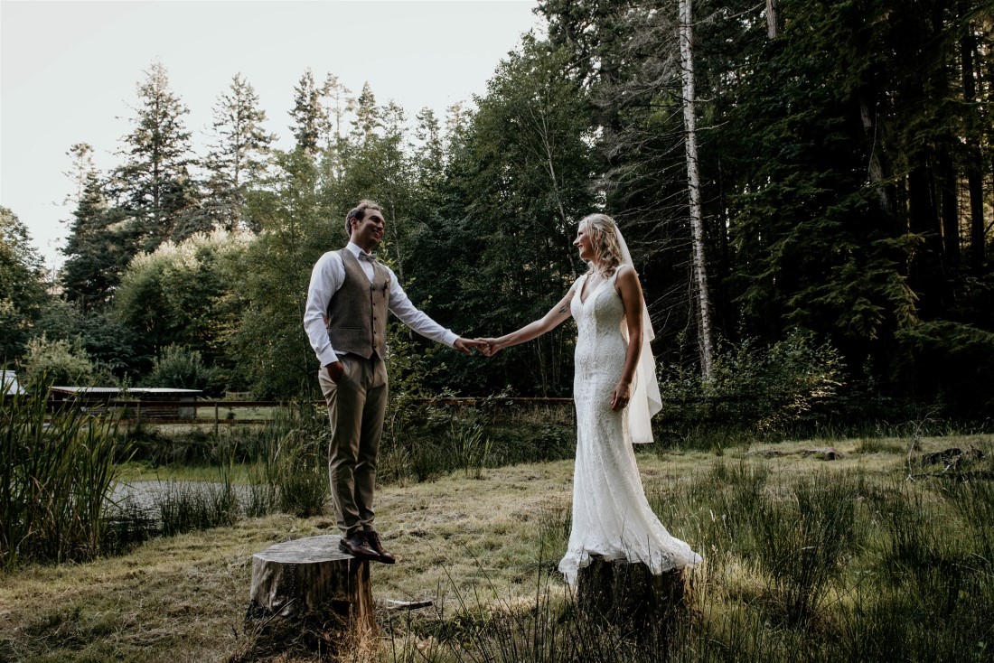 Bride and groom stand on tree stumps in Vancouver Island forest