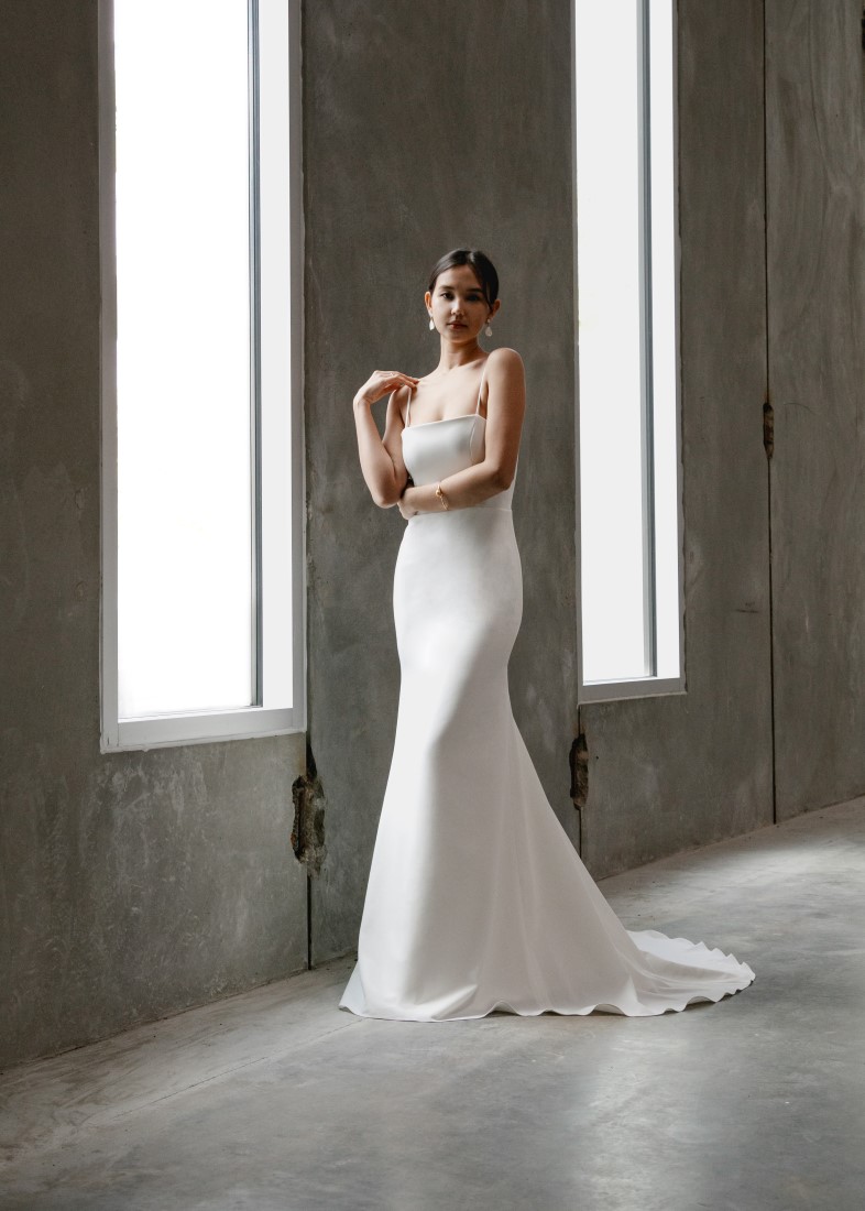 Aesling Crepe wedding dress with a straight-across neckline and spaghetti straps. The back dips into a scoop with a zip up back, and the skirt is a form-fitting mermaid shape Vancouver