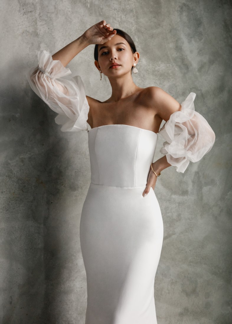 Aesling strapless crepe wedding dress with silk organza puff sleeves and a mermaid skirt. The structured bodice has a zipper back and each puff sleeve is secured with a pearl button.