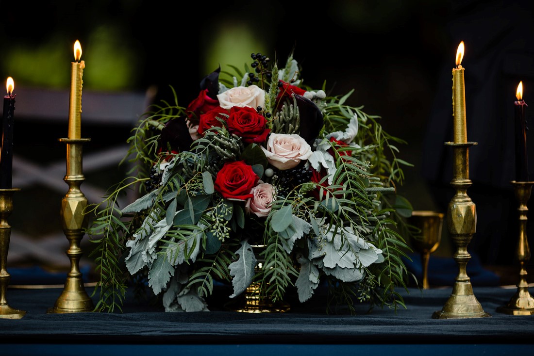 Red Roses, White Roses and Dusty Miller bouquet on wedding reception table 