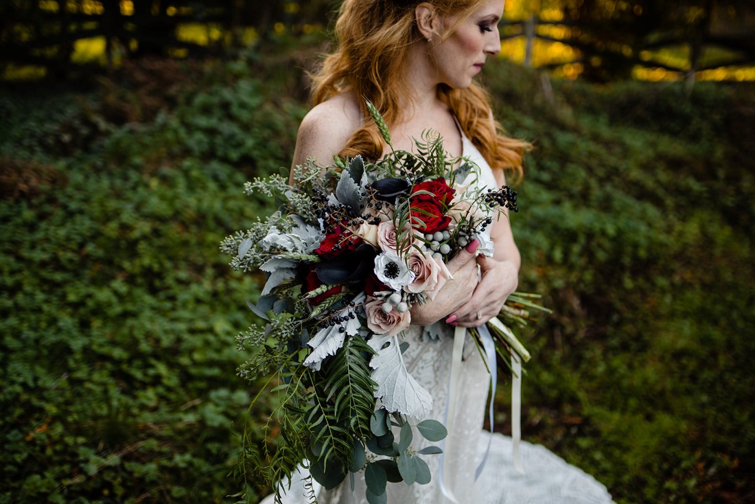 Bride holds bouquet in her arms filled with anemone, roses and dusty miller in Vancouver