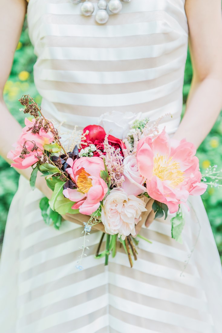 Bridal bouquet of pink peony, white roses against grey and white striped gown by Majesty Bespoke Vancouver