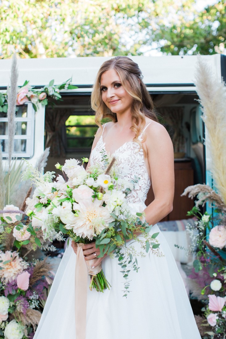 Bride holds large white floral arrangement by Denise Lin Photography