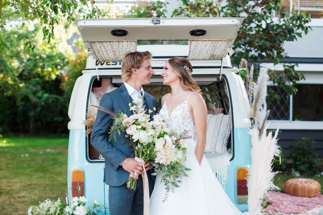 Wedding Couple Stands at back of blue and white Volkswagen van