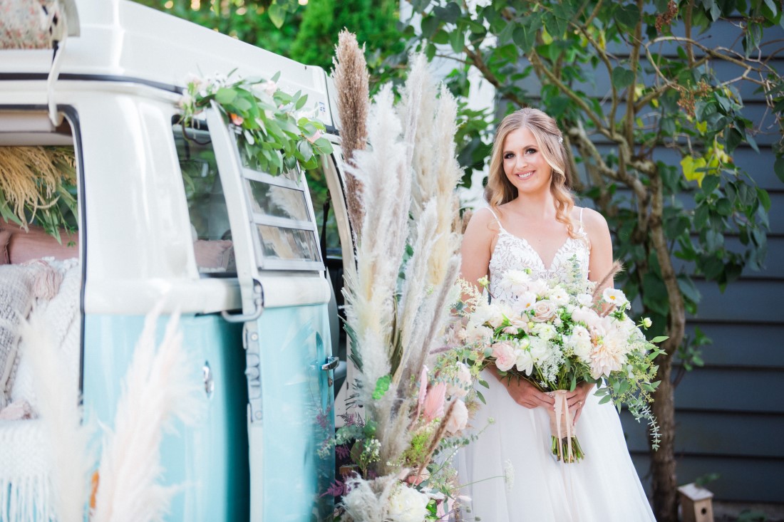 Bride in front of blue and white Volkswagen van with pampas grass