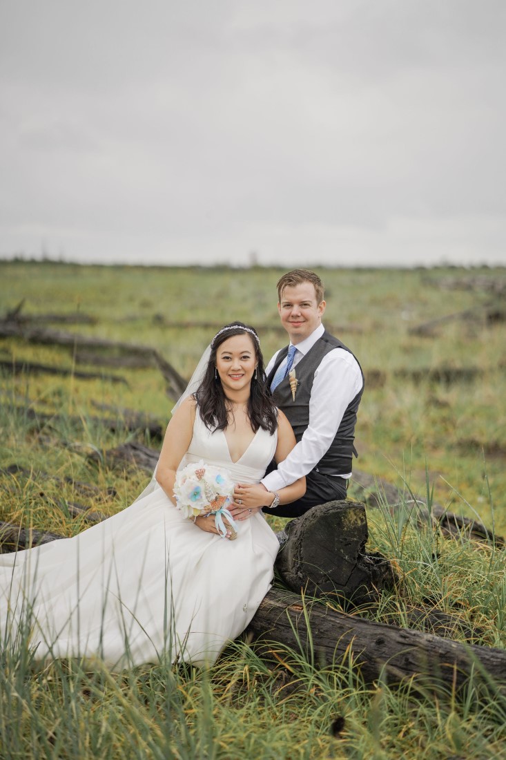 Bride and Groom sit in grassy field near Vancouver